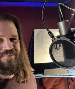 Jon Passow stands in front of the microphone ready to deliver the script's lines.