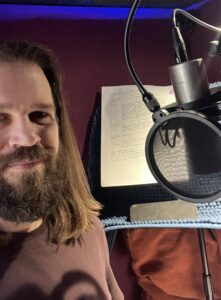 Jon Passow stands in front of the microphone ready to deliver the script's lines.